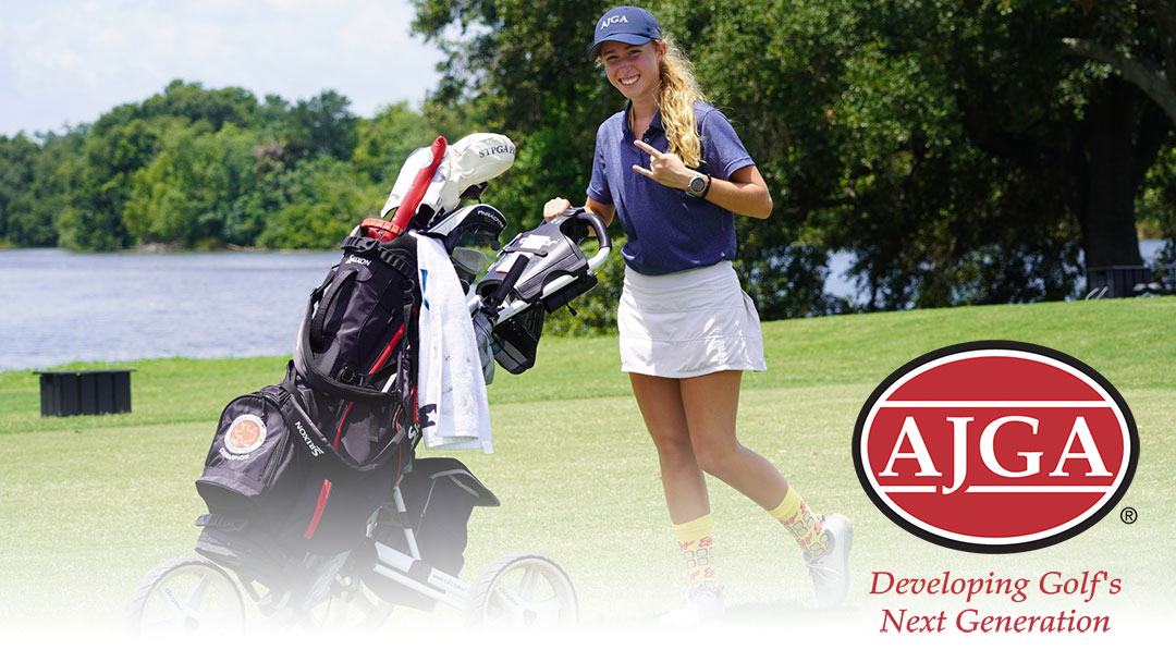 American Junior Golf Association girl golfer pushing golf bag caddie and smiling